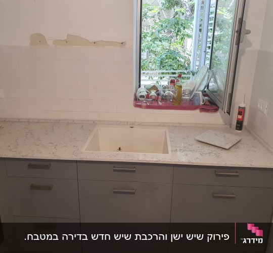 משטח שיש בהיר למטבח עם כיור מותקן על ארונות אפורים